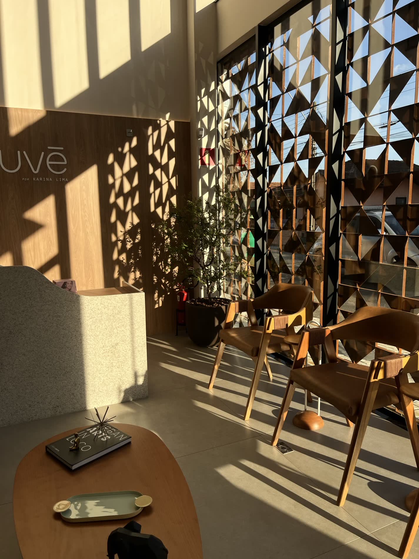 Recepção da Nuvê em luz dourada de fim de tarde, com brise vazado e parede assinada